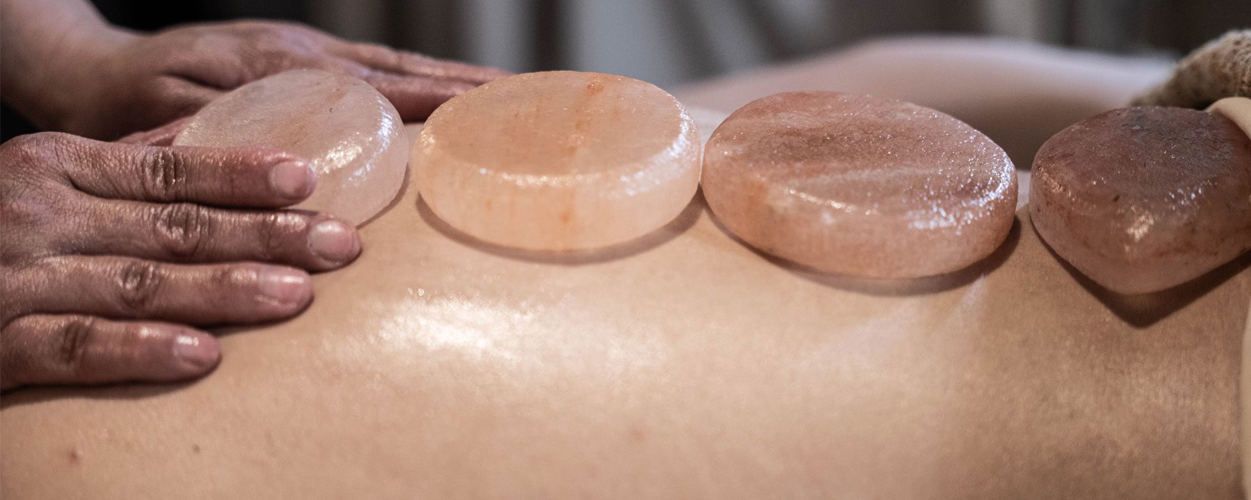 Heated Himalayan stones placed along a guest's back at Zen'd Out